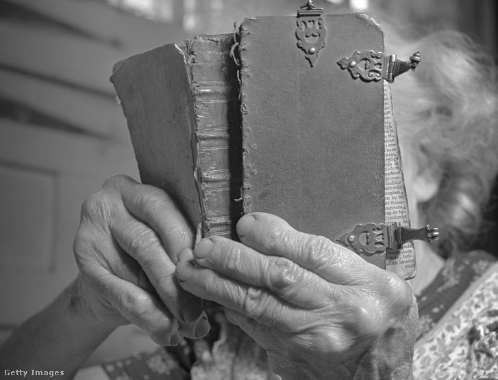 Régi könyvet olvasó Idős asszony kezei jellegzetes, reuma okozta elváltozásokkal