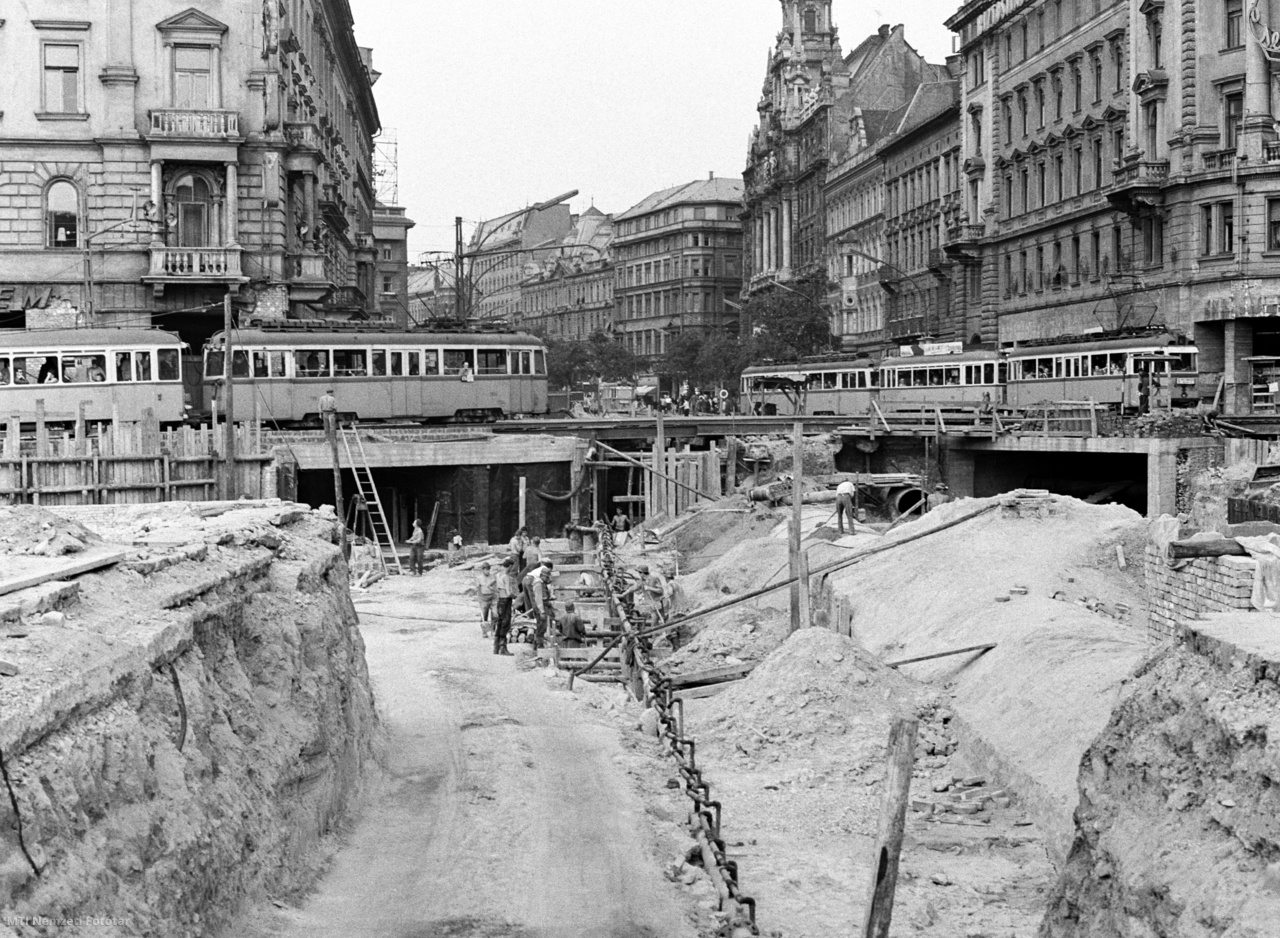 Budapest, 1966. május 18. Épül a gyalogos-aluljáró a fővárosi Blaha Lujza téren. Százhatvan munkás éjjel-nappal dolgozik a Nagykörút és a Rákóczi út kereszteződésénél. Vákuumos rendszerrel több mint két méterrel az átlagos szint alá szorították a talajvizet, így száraz körülmények között jó minőségű alapot készíthetnek. Elkezdték az aluljáró tetőszerkezetét tartó oszlopok sávalapjainak betonozását és a hatalmas szennyvíz-főgyűjtő csatorna átépítését is. Teljesen elkészültek a felszínre, a kivezető lépcsőfeljáró alagutak is mind a kereszteződés mind a négy oldalánál.