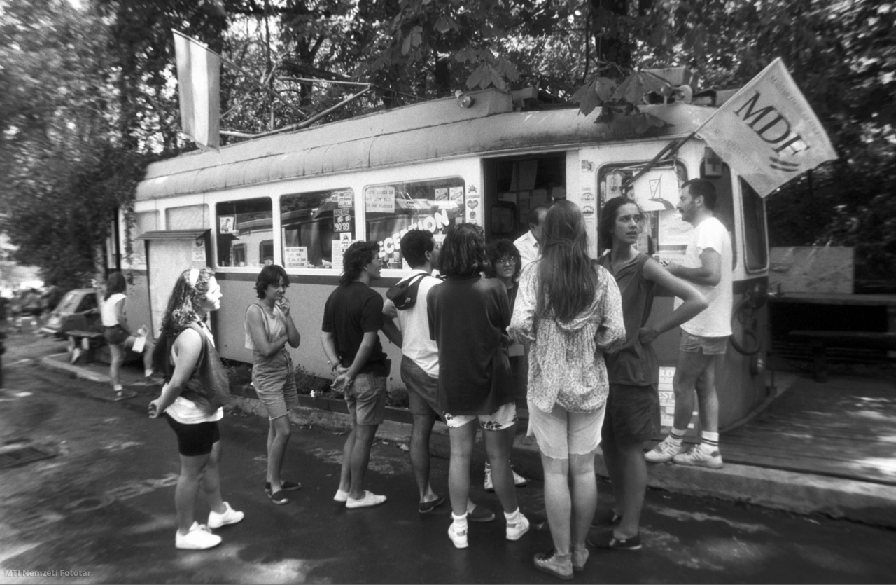 Budapest, 1990. augusztus 15. Nyaraló külföldi turisták állnak az 58-as villamos végállomásánál kialakított kemping egyik villamosszerelvényénél Zugligetben. A büfét és a recepciót a villamosokban, az éttermet a régi állomásépületben alakította ki egy vállalkozó.