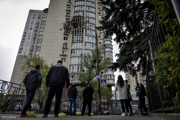 Járókelők egy kijevi lakóépületnél, amelybe dróndarabok csapódtak 2023. május 8-án.