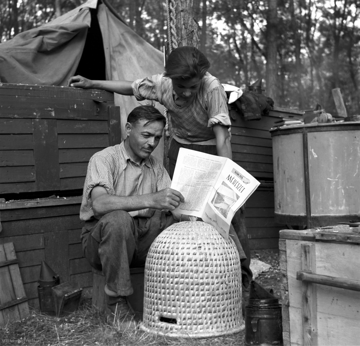 Magyarország, 1954. június 14. Szarvas József méhészmester (b) és Kérdő Lajos méhésztanuló a Mátrában végzett napi munka befejezése után az Üzemi és háztáji méhészet című szaklapot tanulmányozzák. A felvétel készítésének pontos helyszíne ismeretlen.