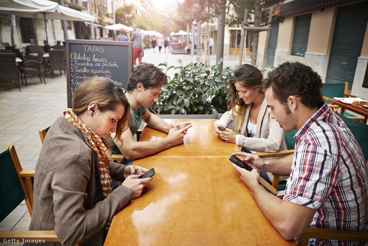 Telefonozó fiatalok egy étteremben. (Fotó: Klaus Vedfelt / Getty Images Hungary)