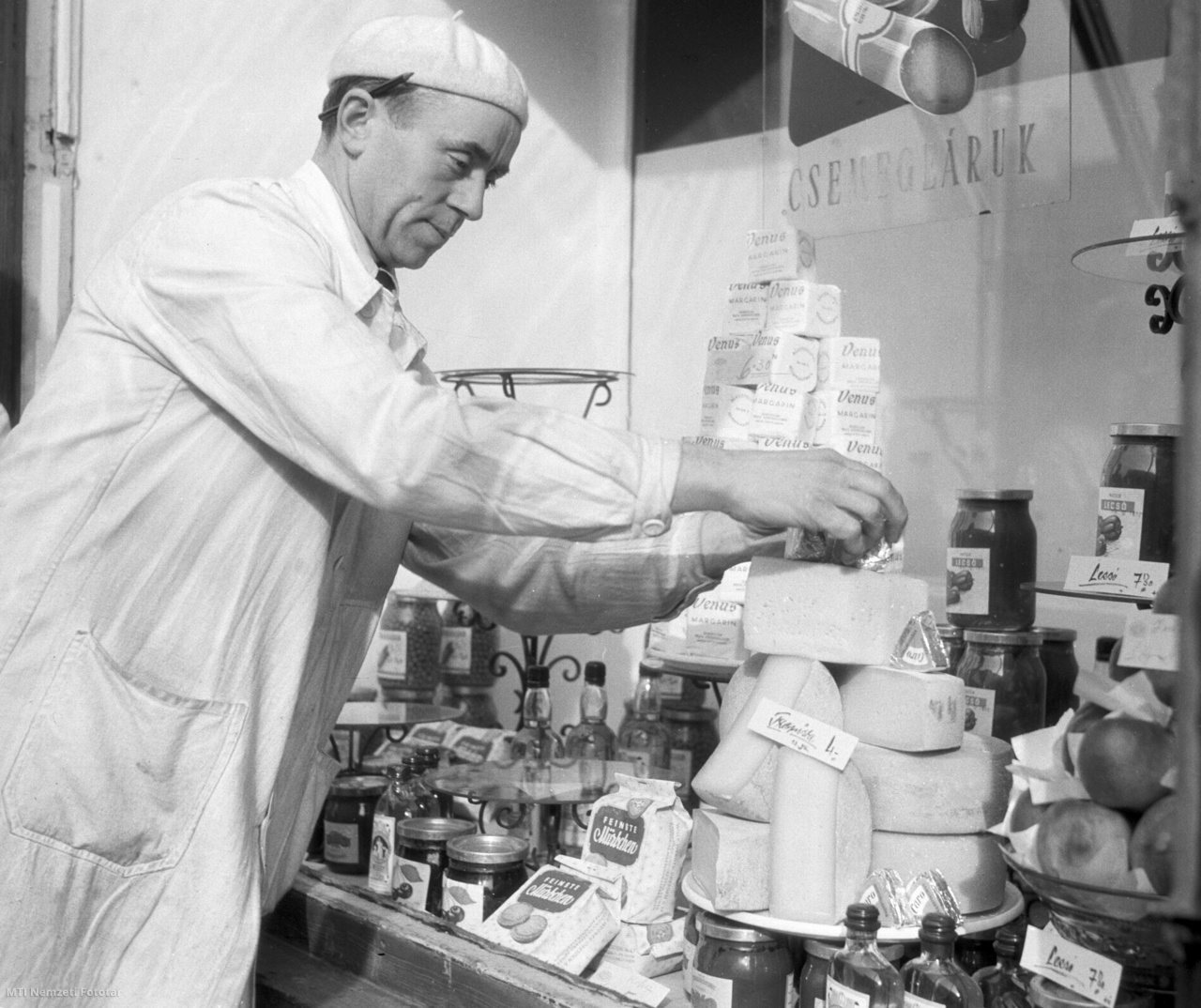 Budapest, 1957. február 8. Az eladó sajtokat pakol az üzletben a csemegeáruk kínálópolcánál.