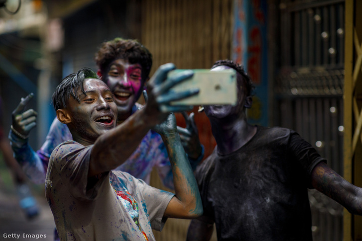 Színes festékkel borított bangladesi fiatalok fotózzák magukat a hindu tavaszünnepen Dakkában 2023 márciusában