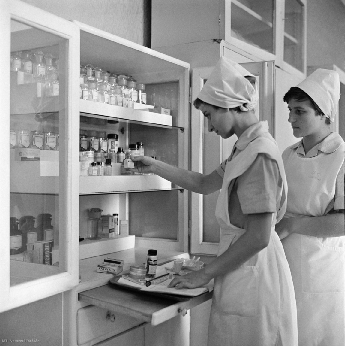 Budapest, 1964. július 24. A gyógyszereket készítik elő a betegeknek a Fővárosi Ápolónőképző Iskola növendékei. A 15 éves fennállását ünneplő oktatási intézményben 1949 óta, több mint ezer középfokú egészségügyi dolgozó szerzett ápolónő-, csecsemőgondozó-, vagy védőnő képesítést. A bentlakó növendékek két évig, a bejárók három évig tanulnak. Az óraadó szakorvosokon kívül jelenleg 11 nevelő oktatja a növendékeket és az ápolónő jelöltek a VIII. kerületi Vas utca 17. szám alatt lévő Balassa János Kórházban végzik a gyakorlatot.