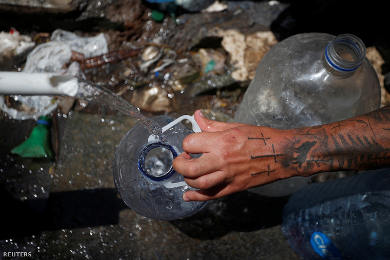 Egy menedékkérő vizet tölt egy palackba egy nyilvános vízforrásból, miközben arra vár, hogy megpróbáljon átjutni az Egyesült Államokba.
