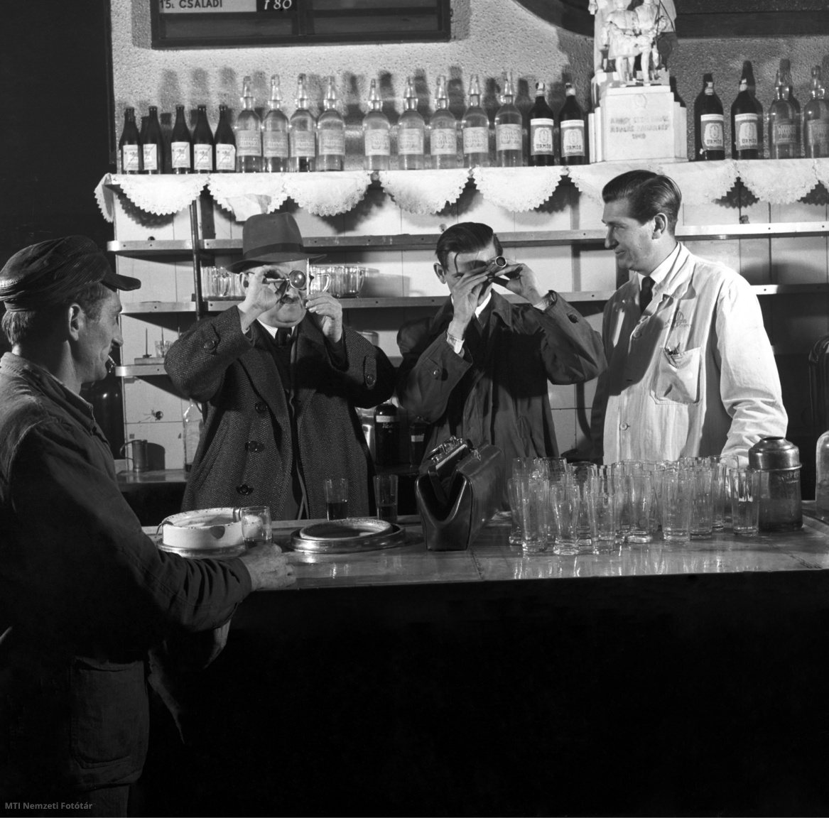 Budapest, 1954. október 4. Dr. Hajós György és Nagy Alajos, a Boripari Kutató Intézet munkatársai szeszfokolóval és refraktométerrel ellenőrzik a Gül Baba étterem söntésében a kimért borok minőségét. Az intézet ad szakvéleményt a forgalomba kerülő borok minőségéről, ellenőrzi a borforgalmi vállalatok laboratóriumait és pincészetét, valamint az italboltok borkezelését is