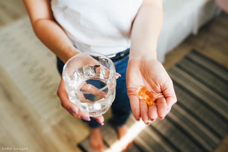 A lány magnézium tablettát, vitaminokat és egy pohár vizet tart (Fotó: Maryna Terletska / Getty Images Hungary)