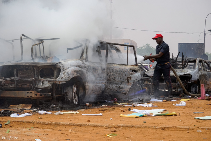 Vízsugárral locsolja egy tűzoltó a felgyújtott autók roncsait Niger fővárosában, Niameyben 2023. július 27-én, miután a puccsot végrehajtó Amadou Abdramane ezredes a fegyveres erőivel eltávolította Mohamed Bazoum elnököt a hatalomból