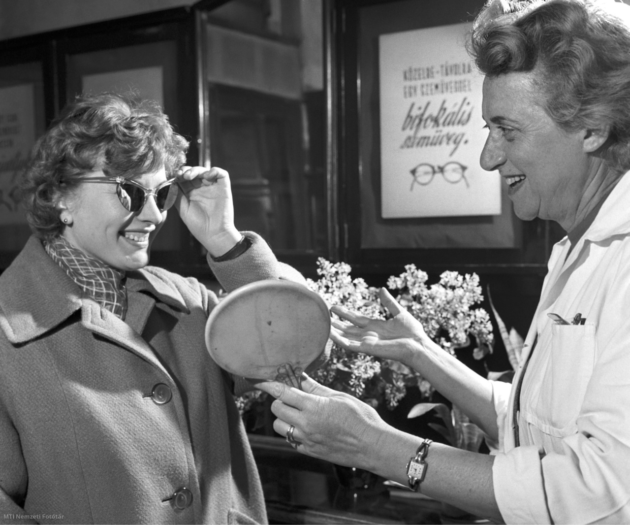 Magyarország, 1960. május 6. Egy nő napszemüveget próbál egy optikusszaküzletben. A felvétel készítésének pontos helyszíne ismeretlen