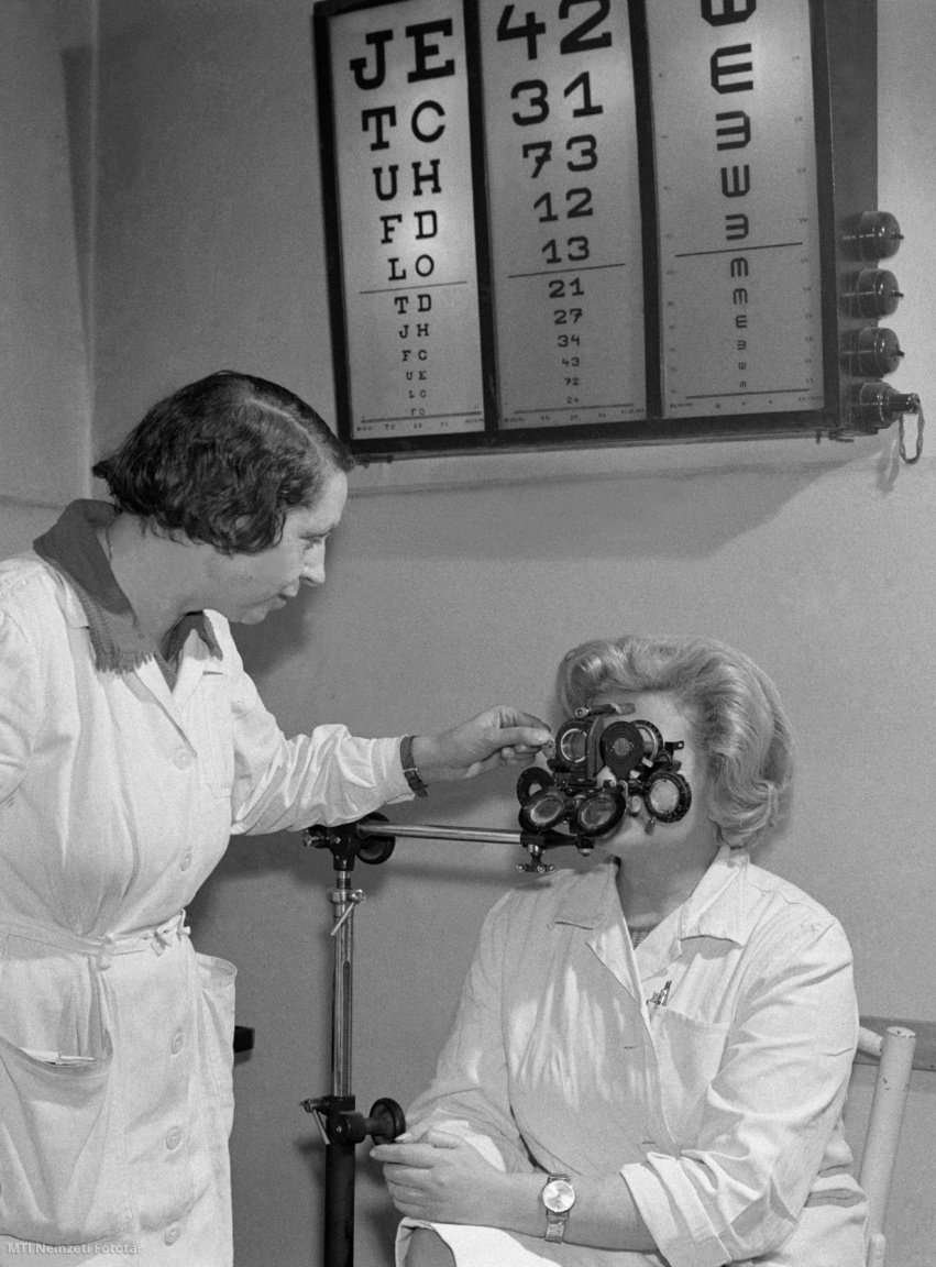 Budapest, 1965. december 16. Deák Katalin (b) Láng Istvánné szemészeti látásvizsgálatát végzi az Országos Testnevelési és Sportegészségügyi Intézetben (OTSI). Az Egészségügyi Minisztérium sportkórházának feladata a sportolók egészségvédelme, a betegségek megelőzése, illetve gyógyítása, aminek érdekében évente mintegy 225 ezer vizsgálat és kezelés folyik. A kutatási osztály tudományos vizsgálati módszerek kidolgozásával segíti közvetlenül a sportorvosok diagnózis munkáját, közvetve pedig az edzőket abban, hogy a versenyzők jobb eredményeket érhessenek el. A kutatások bizonyítják, hogy a mozgás ma már gyógyítóelem, a műtétek, szülések után alkalmazott gyógytorna pedig kedvező hatású. Az OTSI szakmailag irányítja az ország sport-rendelőintézeteit is, és az iskolaorvosok részére előadásokat tartanak a gyógyító testnevelés országos méretű kiterjesztése érdekében. A háttérben a látásvizsgáló tábla