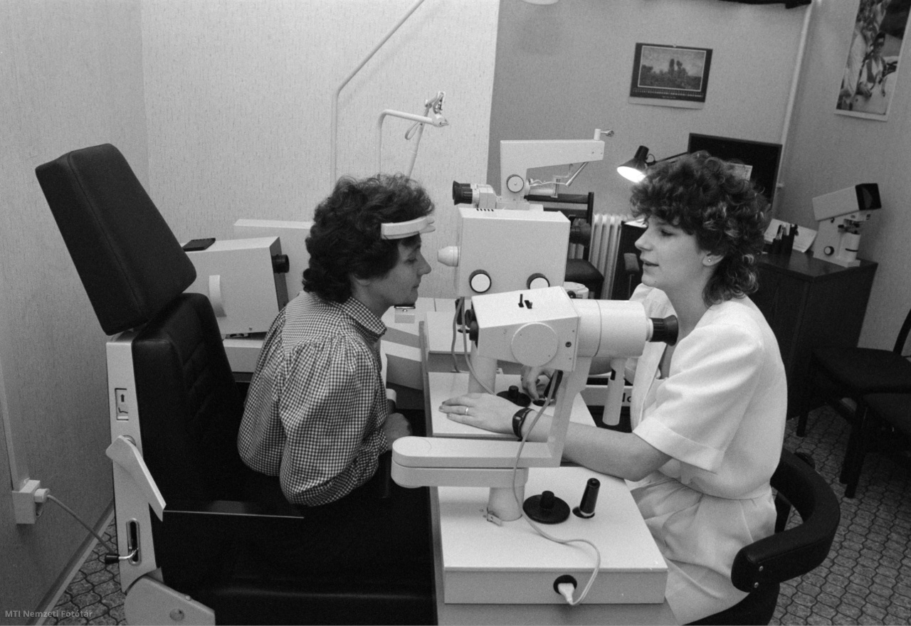 Dunaújváros, 1987. május 28. Az optikus műszeres szemvizsgálatot végez egy nőn a vidéken elsőként Dunaújvárosban létesített az OFOTÉRT a MOM Granvisus céggel közösen létesített, ZEISS szemvizsgáló műszerrel ellátott optikai szakboltjában.