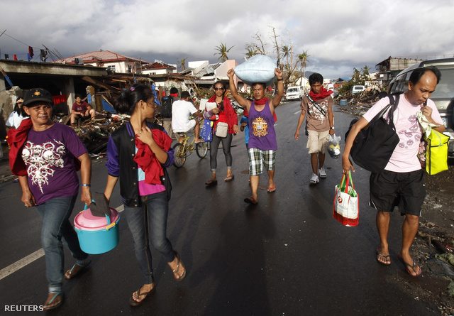 Egy zsák rizst visz a fején egy férfi a tájfun által letarolt Tacloban város utcáján