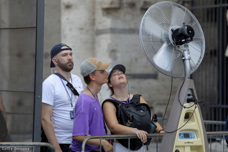 Turisták frissítik magukat egy porlasztott vizet fújó ventilátorral egy fülledt napon Rómában, Olaszországban 2023. július 18-án
