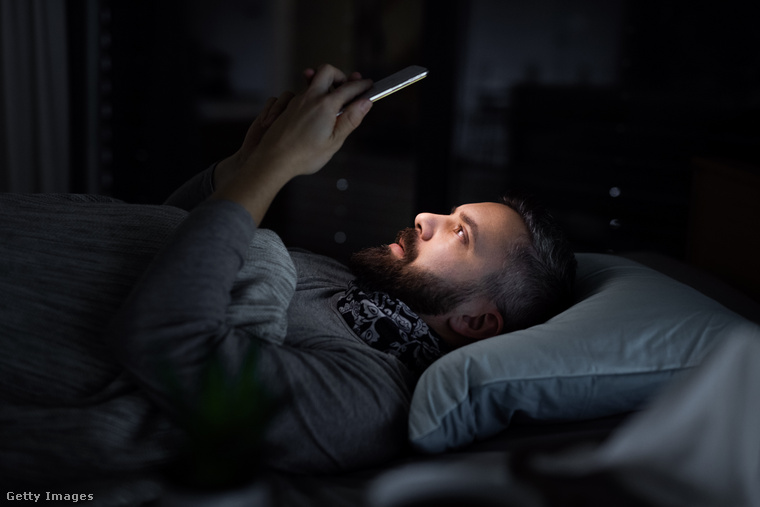 A szakértők azt javasolják, hogy legalább a lefekvés előtti fél órában ne nézzünk rá az eszközünk képernyőjére, amiben segít, ha az ágyunktól távolabb tartjuk telefonunkat. (Fotó: Halfpoint Images / Getty Images Hungary)