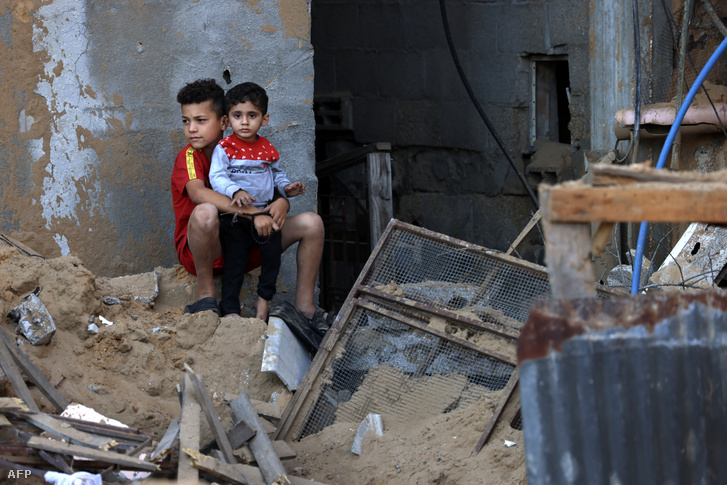 Palesztin fiúk nézik a károkat egy izraeli katonai csapás után a Gázai övezet déli részén lévő rafahi menekülttáborban 2023. október 15-én
