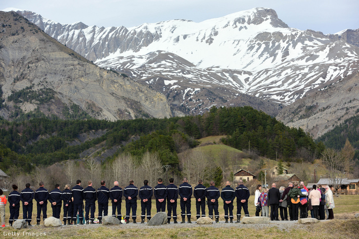 Rokonok állnak a Germanwings 4U9525-ös járata áldozatainak emlékművénél a lezuhanás helyszínéhez közeli hegyek előtt 2015. március 26-án Le Vernet-ben, Franciaországban