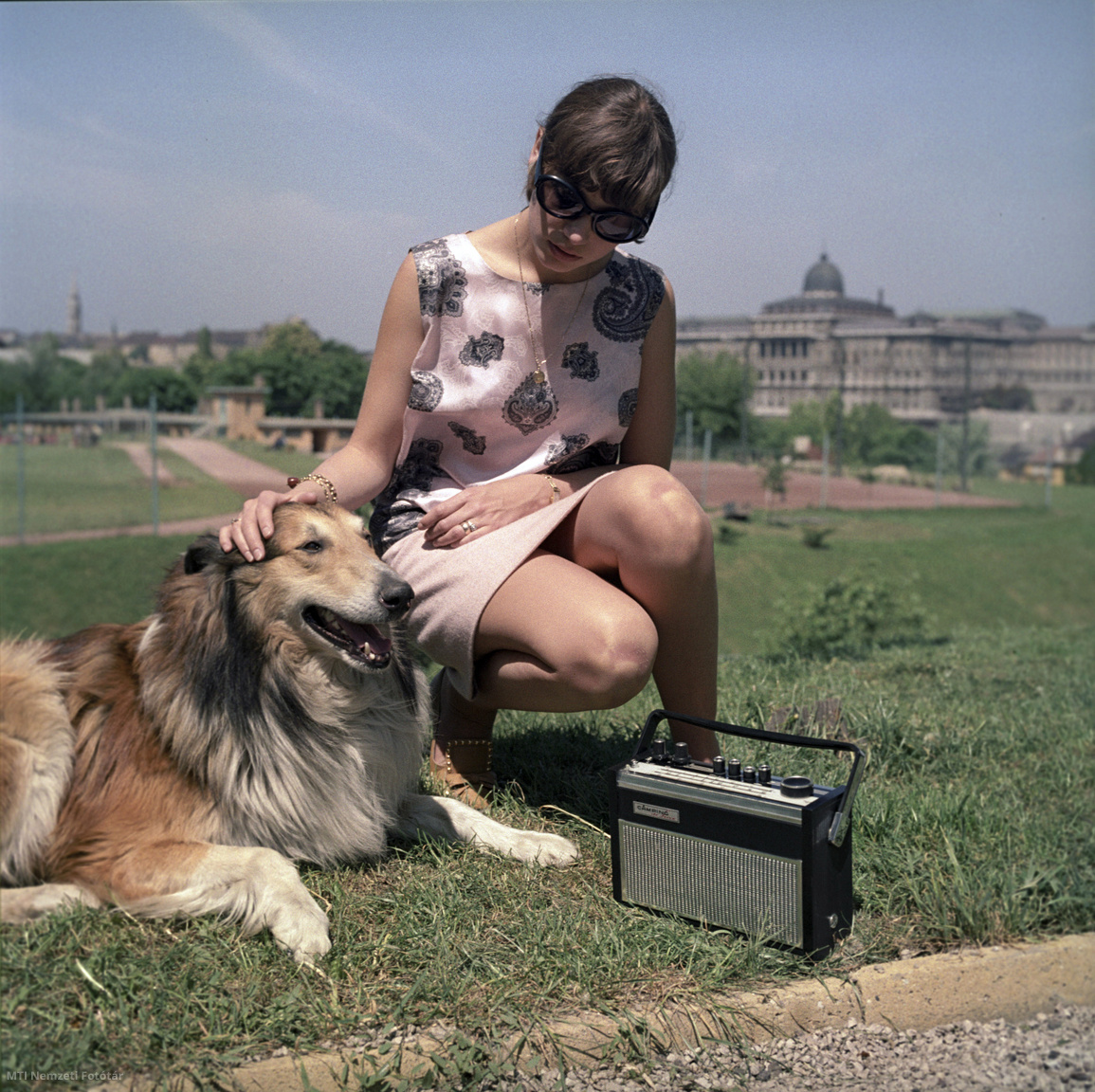 Budapest, 1968. május 10. Modell egy kutyával reklámozza a VIDEOTON Rádió- és Televíziógyár Videoton BR113 Camping de Luxe típusú 10 tranzisztoros, három, illetve négy hullámsávos, AM/FM üzemmódú, ferrit és teleszkópantennával felszerelt táskarádió-családjának egyik tagját a Naphegyen, a Czakó utcai sportpályán, a gyár számára készülő naptárhoz. A háttérben a budai Várpalota