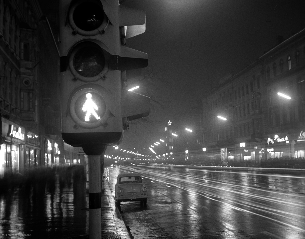 Budapest, 1964. december 10. Gyalogos-átkelőhelynél szabad jelzéssel világító forgalomirányító közlekedési lámpa az esti kivilágítású Rákóczi úton.