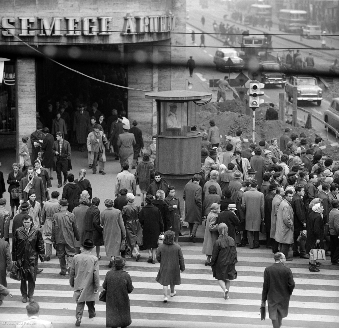 Budapest, 1965. november 3. Járókelők várakoznak, illetve haladnak át a szabad jelzésen a fővárosban a Blaha Lujza téren, a Rákóczi út és a Lenin körút találkozásánál, a Csemege Kereskedelmi Vállalat Élelmiszer Áruháza, az úgynevezett éjjel-nappalinál lévő gyalogátkelőhelyeknél, a rendőri forgalomirányító torony mellett.