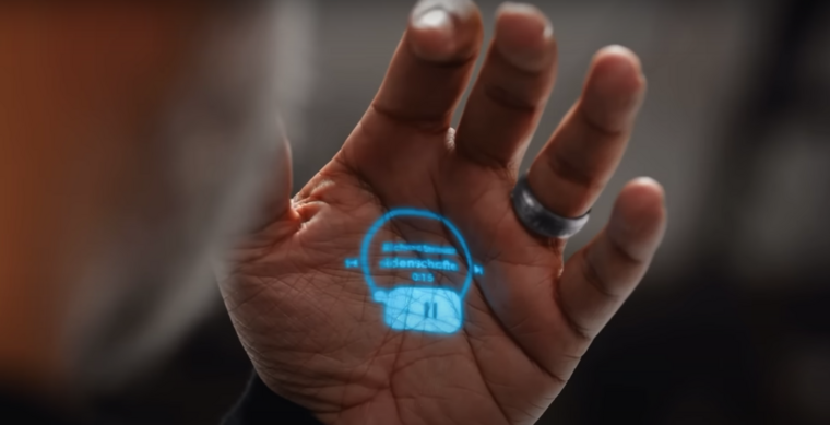 A vezérlés hangalapú, és a kommunikáció Bluetooth fülhallgatón keresztül, valamint gesztusokkal történik, miközben a kijelző helyett a tenyerünkön jeleníti meg az információkat. (Fotó: youtube)