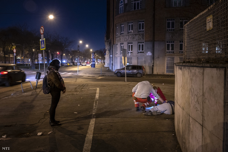 A Magyar Máltai Szeretetszolgálat önkéntesei egy hajléktalant vizsgálnak a budapesti Fiumei úton 2021. február 26-án