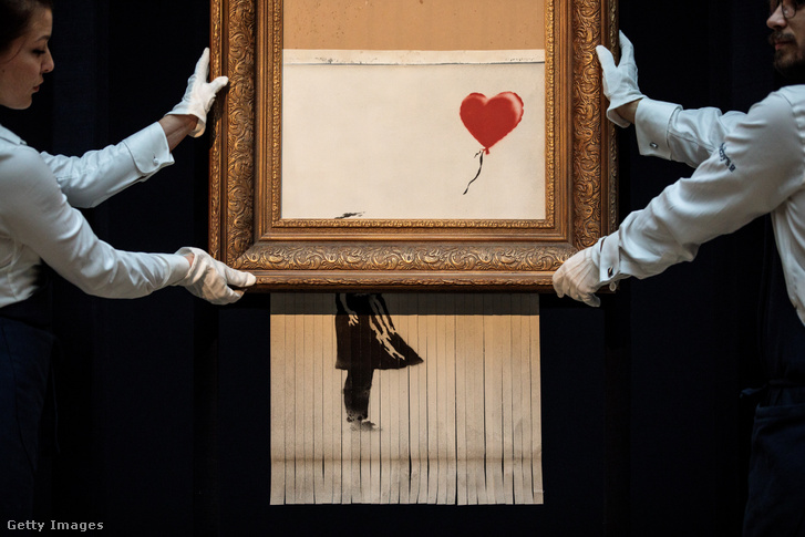 A Sotheby's alkalmazottai pózolnak Banksy brit művész "Love is in the Bin" című művével a Sotheby's aukciósház sajtóbemutatóján Londonban, az Egyesült Királyságban 2018. október 12-én