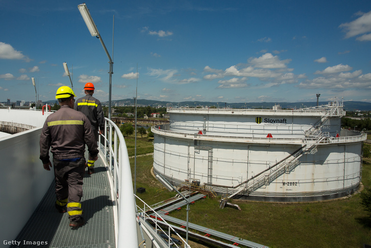 Munkások sétálnak a Slovnaft Oil Review egyik kőolajat tároló silója körül a szlovákiai Pozsonyban 2022. május 31-én