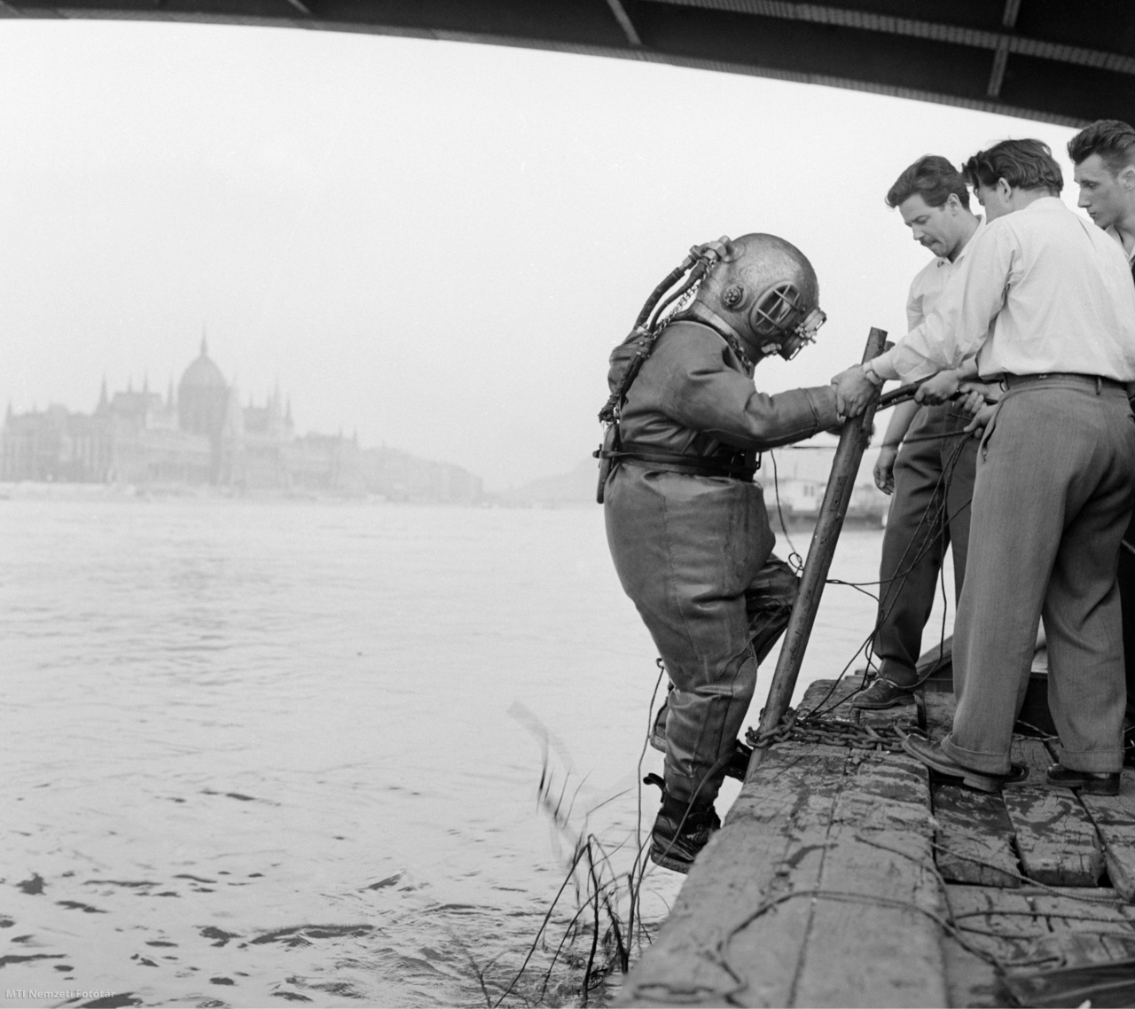 Budapest, 1960. május 24. Sólyom János MHS nehézbúvár feljön a vízből  a Margit híd háborúból visszamaradt roncsainak kutatása során. A kiemelt fémrészek értékesítéséből származó összeget a szakosztályok fejlesztésére fordítják. Az eredeti felvétel készítője ismeretlen.