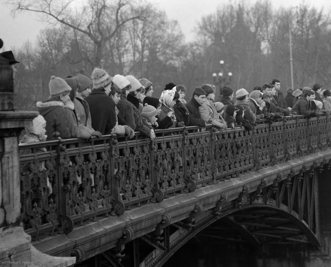 Budapest, 1965. december 28. Kíváncsiskodók nézik az iskolai szünetben korcsolyázókat a Városligeti Műjégpályán, a Városligeti-tó medrében, illetve partján kialakított téli sportlétesítményben, a Kós Károly sétányt a Hősök terével a Városligeti-tó fölött összekötő hídról. Naponta 14-15 ezer látogatója van a Városligeti Műjégpályának.