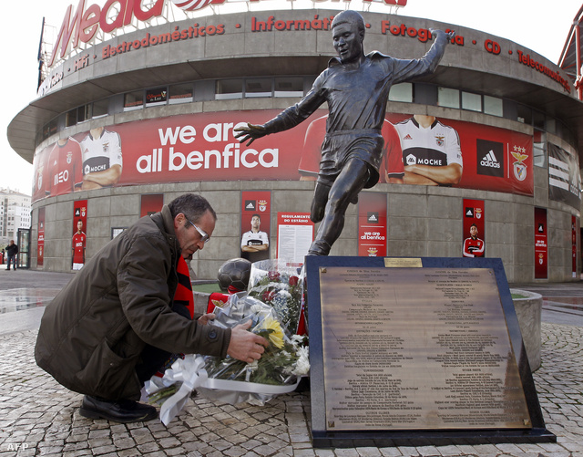 Egy Benfica szurkoló virágcsokrot helyez el Eusébio szobránál a Luz stadion előtt Lisszabonban