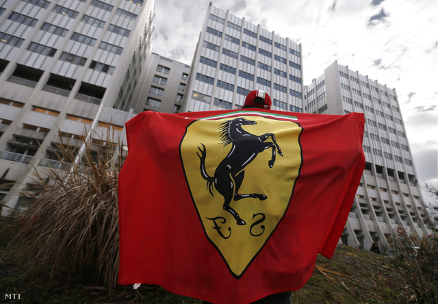 Egy rajongó Ferrari zászlóval Schumacher korábbi csapata, a Ferrari által szervezett csendes ünnepségen Grenoble egyetemi kórháza előtt