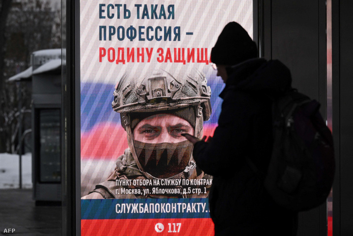 Egy személy az orosz hadsereg szerződéses katonai szolgálatot hirdető reklámplakátja előtt várakozik egy buszmegállóban 2023. december 5-én