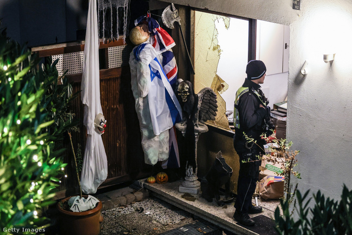 Egy rendőr áll egy gyanúsított reichsbörgeri lakásának lerombolt bejárata előtt 2023. december 8-án
