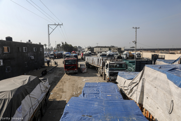Az UNRWA és a Vörös Félhold által küldött humanitárius segélyt szállító teherautók áthaladnak az egyiptomi határon lévő rafahi átkelőn, miközben az UNRWA egyik raktárába hajtanak a gázai Rafahban 2023. december 18-án