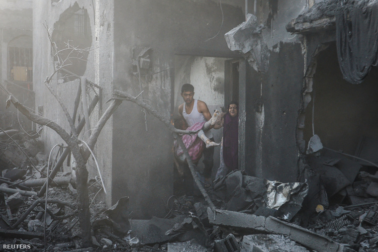 Egy férfi egy sebesült palesztin lányt ment ki egy épületből a Gázai övezet déli részén 2023