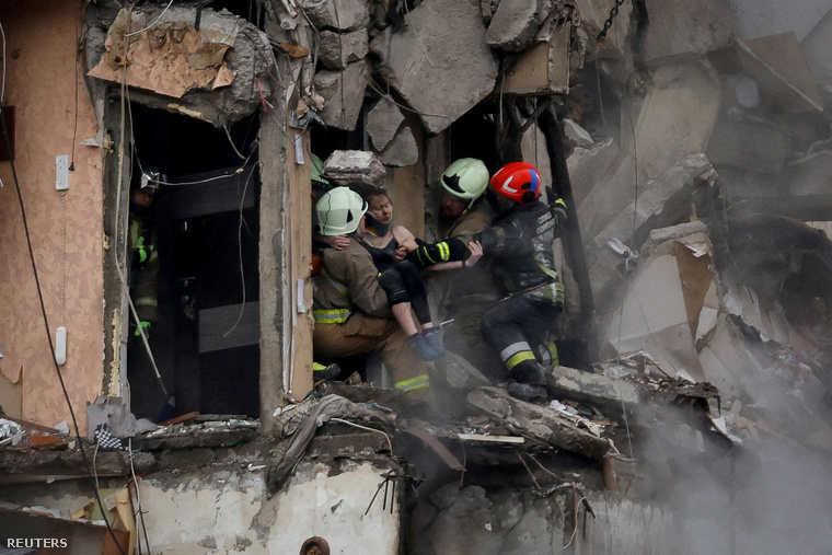 A mentőszolgálat munkatársai evakuálnak egy nőt egy lakóházból, amelyet rakétacsapás ért Dnyipro városában, Ukrajnában 2023