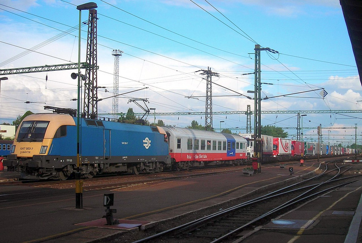 RoLa, azaz Rollende Landstrasse (guruló országút) vonat Kecskemét állomáson még a vonatnem megszüntetése előtt. Az ilyen vonatokon a sofőrök a személykocsiban pihennek, amíg az igazán nagy távolságokat vasúton teszik meg, így üzemanyagot és általában menetidőt is spórolva. - Fotó: Balogh Zsolt / Wikimedia Commons
