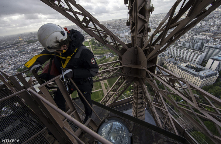 Munkás dolgozik a párizsi Eiffel torony díszkivilágításán 2015. május 6-án