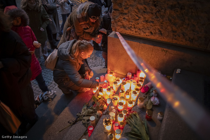 Emberek gyertyát gyújtanak a Károly Egyetem Filozófiai Karának épülete előtt a 2023. december 22-i tömeges lövöldözést követően