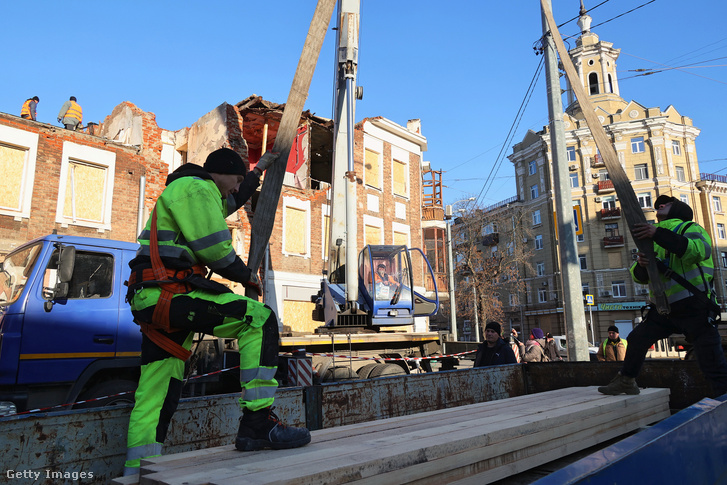Építőmunkások javítanak egy épület tetejét, amelyet az orosz ágyúzás megrongált Harkivban, 2023. november 30-án