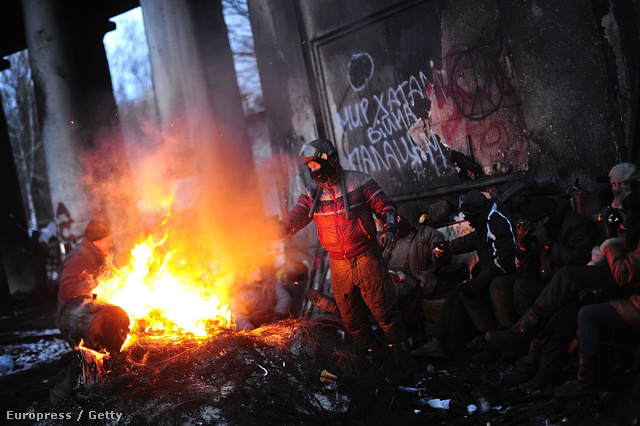 Tüntetők melegednek a Grusevszkaja utca barikádjai mellett rakott tűznél, 2014. január 29-én. A Majdan mellett a Dinamo-stadion melletti utca az ellenzéki tüntetés másik fő helyszíne.