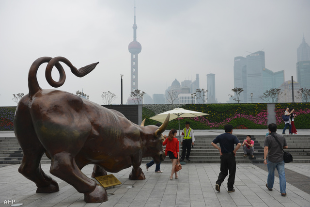 A híres Wall Street-i bronzbika másolatánál pózolnak kínai turisták Sanghajban