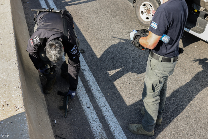 Az izraeli biztonsági erők tagjai egy automata fegyvert ellenőriznek az úton a lövöldözés helyszínén, 2024. február 22-én, a Jeruzsálemtől keletre fekvő Maale Adumim település mellett