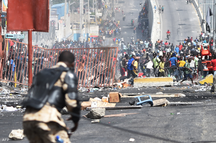 Emberek menekülnek a haiti rendőrség elől, miután kifosztották a Port-au-Prince melletti Delmas település boltjait az üzemanyag árának emelkedése elleni tüntetések során 2018. július 8-án
