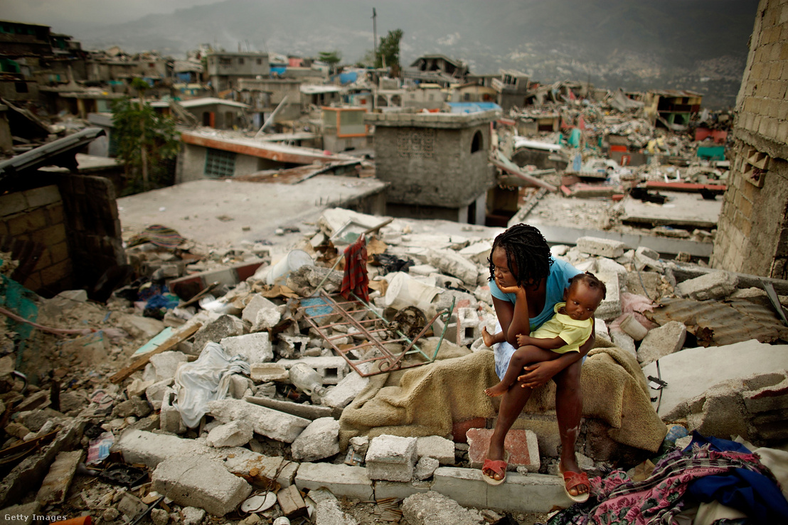 Egy nő és gyermeke ülnek azon a helyen, ahol a 7,0 erősségű földrengés során összedőlt a házuk a Fort National negyedben 2010. február 26-án Port-au-Prince-ben, Haitin