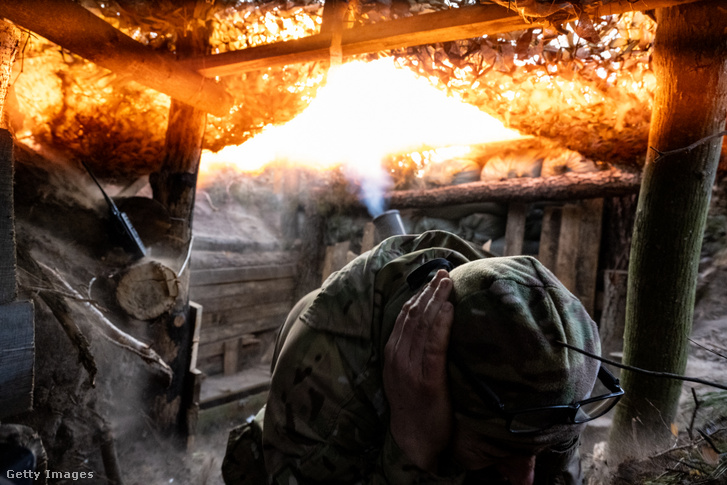 Egy ukrán katona befogja a fülét, miközben egy 120 mm-es aknavető robban 2024. február 17-én Ukrajnában