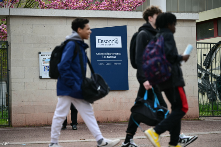 Középiskolások sétálnak a Departmental middle school - Les Sablons feliratú jelzőtábla mellett a Viry-Chatillon-i Les Sablons iskola bejáratánál 2024. április 5-én, egy nappal azután, hogy egy tizenéves fiút megtámadtak, és kórházba szállítottak