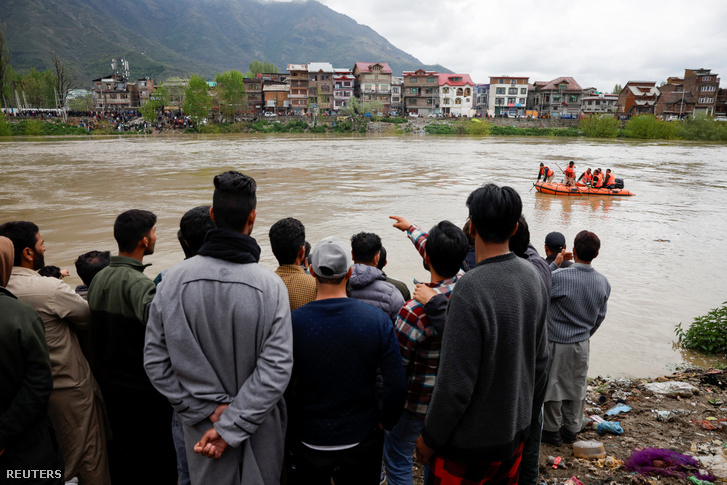 Emberek nézik, ahogy a mentők keresési műveletet hajtanak végre, miután egy embereket, köztük gyerekeket szállító csónak felborult a Dzselum folyóban, Szrinagarban 2024. április 16-án