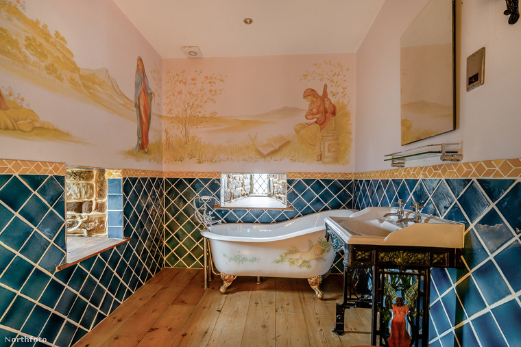 A fürdőszobában egy kád és dupla mosdó található, a helyiségben a kék szín, illetve egy, az előző fürdőszobáéhoz hasonló falfestés dominál.